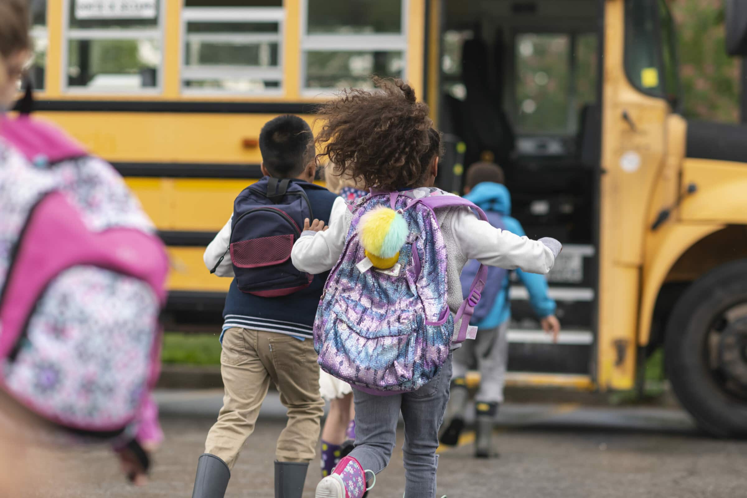 A group of children running towards a school bus