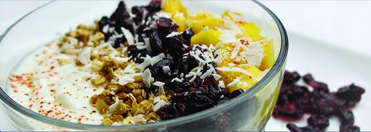 Vanilla yogurt topped with granola, mano, coconut and dried cranberries